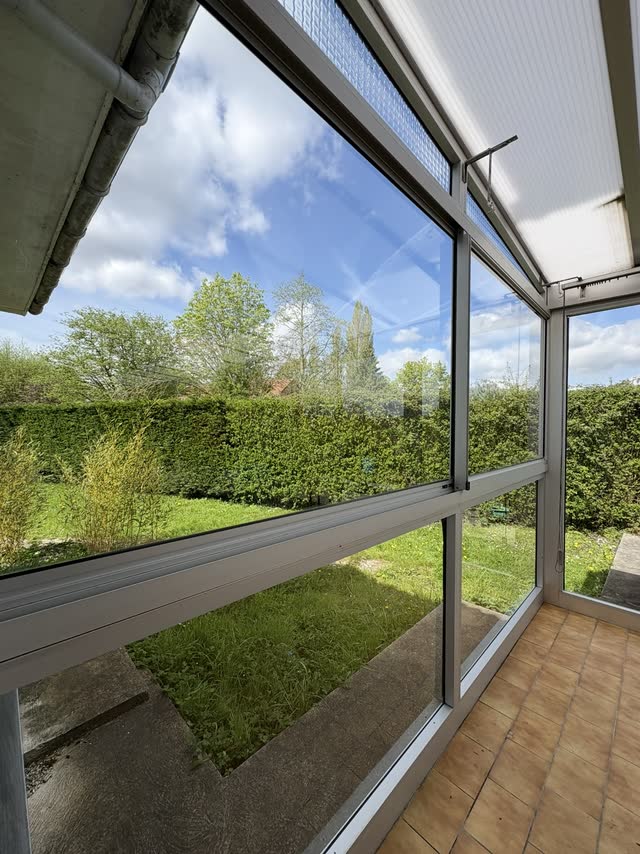 Véranda vue de l'intérieur, vitrages nettoyés donnant sur un jardin