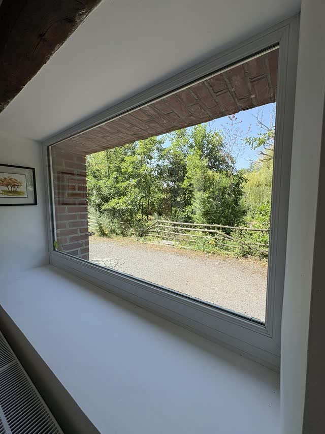Grande baie vitrée fixe d'une maison, vue dégagée sur le jardin après nettoyage